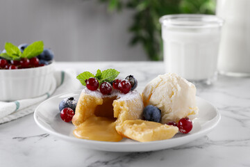 Tasty vanilla fondant with white chocolate, berries and ice cream on white marble table
