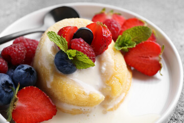 Delicious vanilla fondant served with fresh berries on grey table, closeup