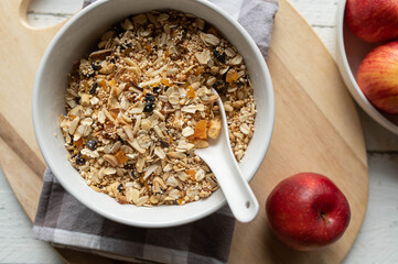 Homemade granola with oats, puffed amaranth, quinoa, almonds, dried fruits such as apricots, plums, apples, and dates in bowl with spoon