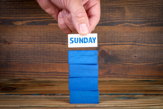 Sunday. Colorful blocks in a pile on a wooden texture background
