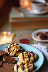 Cup of tea or coffee, plate with desserts, dried oranges, bowl of grapes, scented candles, vintage books, pumpkins and autumn leaves on the table. Autumnal hygge. Selective focus.