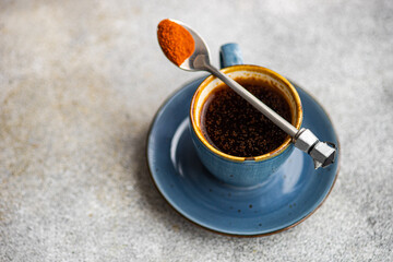 Overhead view of a cup of black coffee with a spoonful of ground paprika