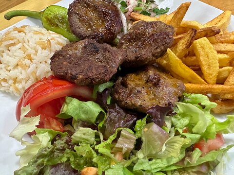 Close-up of Turkish kofta meatballs with chips, rice and salad