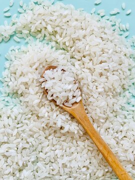 Close-up of a spoonful of uncooked white rice on a stack of rice
