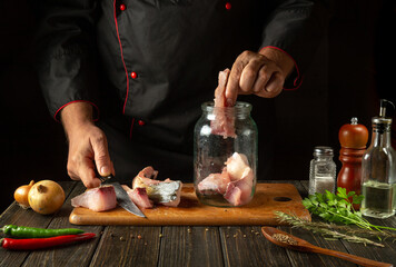 The chef puts steaks with raw fish into a jar. The concept of salting or canning fish at home with spices and coriander