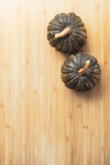 Two whole pumpkins on wooden top, space for text