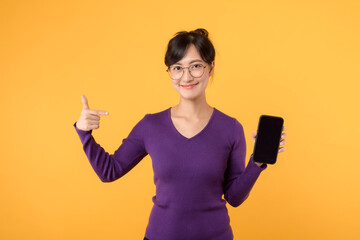 Naklejka premium An attractive lady with a positive expression, wearing a purple shirt and eyeglasses, enjoying her smartphone. Stay connected and succeed in the digital world against a yellow background