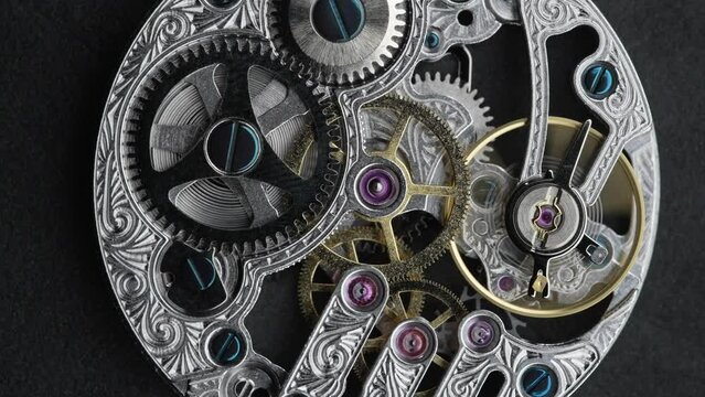 Silver chain and internal working mechanism of an antique pocket watch on a gray background. Screws, moving spring, rotating gears and cogwheels of an old clock.