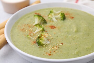 Delicious broccoli cream soup served on light table, closeup