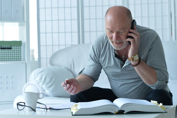  old man with book talking on phone and taking notes