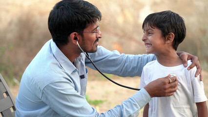 Health checkup, Children medical insurance care. Indian village doctor of pediatrician holding stethoscope checking heartbeat