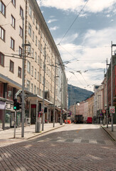 Empty street during the day with bright buildings around and a visible hill, pedestrian crossing