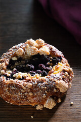 Close-up of a delicious homemade blueberry and custard brioche on a wooden surface. A treat and tasty refreshment.