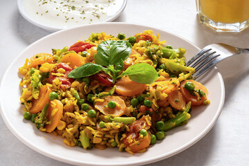 Homemade delicious traditional spicy Indian dish, khichri or khichdi, consisting of rice, lentil, tomatoes, green peas and broccoli, garnished with basil leaves, is served with curd.  