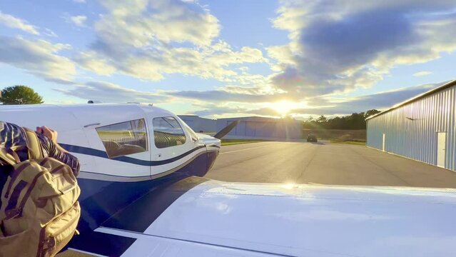 private pilot dismounts wing of piper cherokee 180 with sunset in background