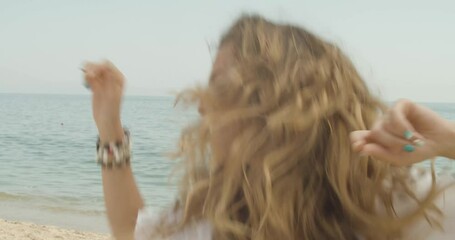 Free-spirited European woman with loose hair dances on beach without inhibitions
