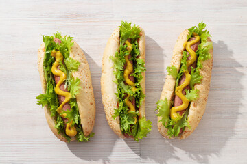 Hot dogs with sauce on wooden background, top view