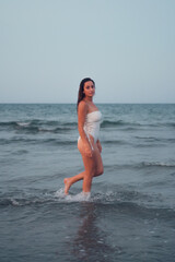 Young beautiful woman poses with the sea in the background at sunset
