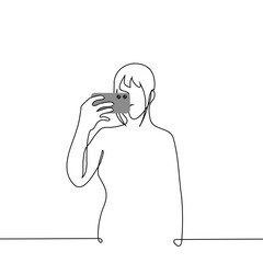 woman stands and films on a mobile phone holding the phone horizontally - one line art vector. concept of shooting video or taking mobile photo