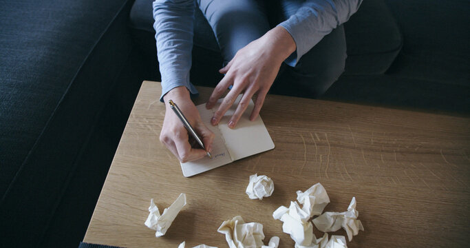 Woman writing a dear John letter with crumpled pages around her