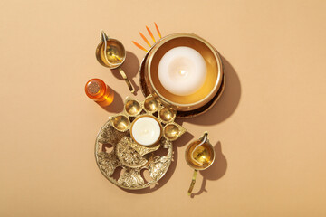 Copper oriental utensils, bottle of oil and candles on beige background, top view