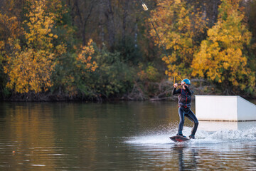 Fototapeta na wymiar Girl on a wakeboard. An athlete performs a trick on the water. Autumn Park