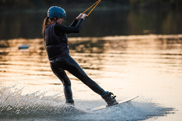 Girl on a wakeboard. An athlete performs a trick on the water. Autumn Park