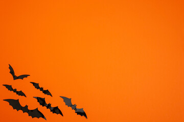 Orange background with bats in the lower left corner. copy space. Halloween