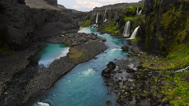 fantasy like canyon valley of tears with several waterfalls falling in the blue river with lush vegetation in the desertic lava landscape Sigoldugljufur iceland