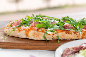 fine restaurant pizza on wooden board with salad, meat and mozzarella 
