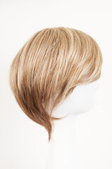 Obraz premium Natural looking blonde fair wig on white mannequin head. Short hair cut on the plastic wig holder isolated on white background, side view.