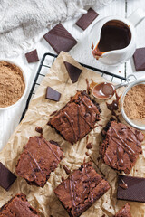 Brownie cut into pieces, coated with chocolate and cocoa, top view.