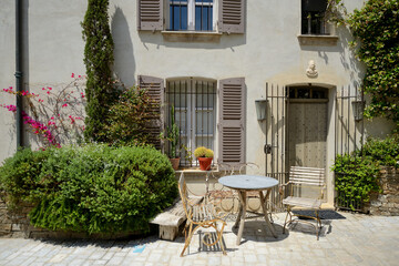 Fototapeta na wymiar View from the street of traditional French townhouse with vintage garden furniture in front of the house - June 2018 - Saint-Tropez, French Riviera (Côte d'Azur), France