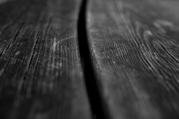 Monochrome close-up of an aged wooden tabletop with its intricate grain and texture