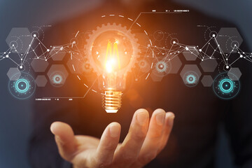 Business idea and financial solution. Light bulb in hand on the background of business skyscrapers. Economy, growth, income concept.