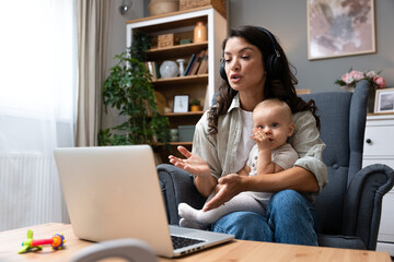 Female business owner work on laptop from home during maternity leave, running private company with baby in her lap, having online video call. Businesswoman mother with toddler working at the computer - Powered by Adobe