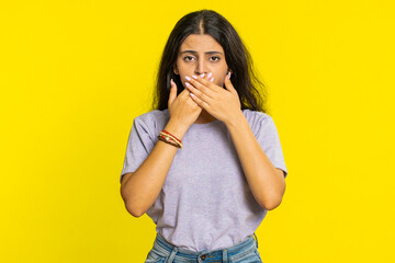 I will not say anything. Frightened Indian woman closing mouth with hands, looking intimidated...