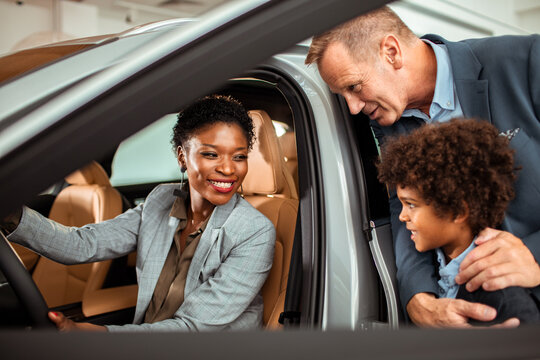 Young mixed family testing out cars at the dealership