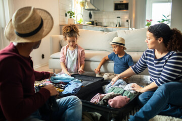 Young mixed family packing their clothes in a suitcase for their trip in the living room at home