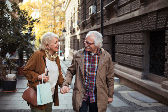 Senior Couple Shopping And Holding Hands On A Walk Downtown In The City