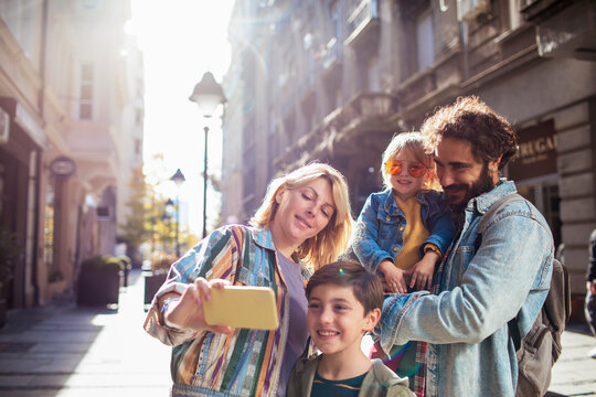 Young family taking selfies on a walk in the city