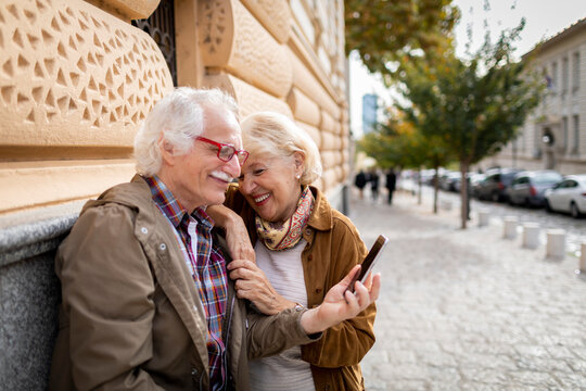Happy senior couple using a smartphone in the city