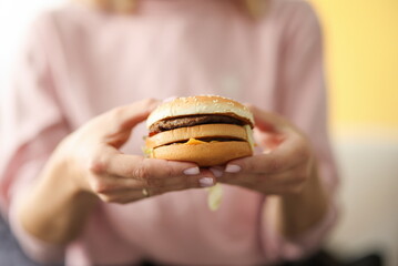Female hands hold hamburger with cheese and meat. Fast delivery and takeaway food concept - Powered by Adobe