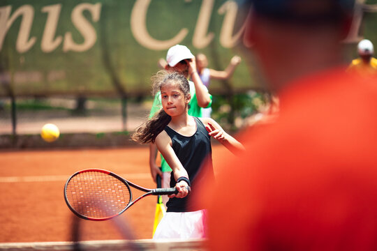 Young female tennis player hitting a forehand on a clay court
