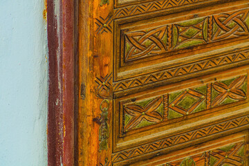 Big old wooden door decorated with various symbolic signs carved directly on the canvas of massif. Example of exterior and interior decoration of entrance lobbies in different cultures around world