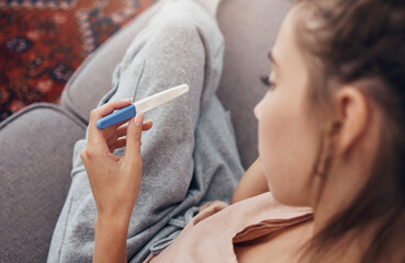 Pregnancy test, waiting and woman on sofa in home, reading news and check results.,Stick, sad and pregnant mother in living room for future maternity, ivf fertility and anxiety, depressed or serious - obrazy, fototapety, plakaty