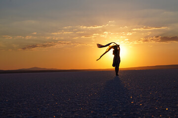 Young ballerina walking on the lake at sunset. young woman walking on the beach at sunset