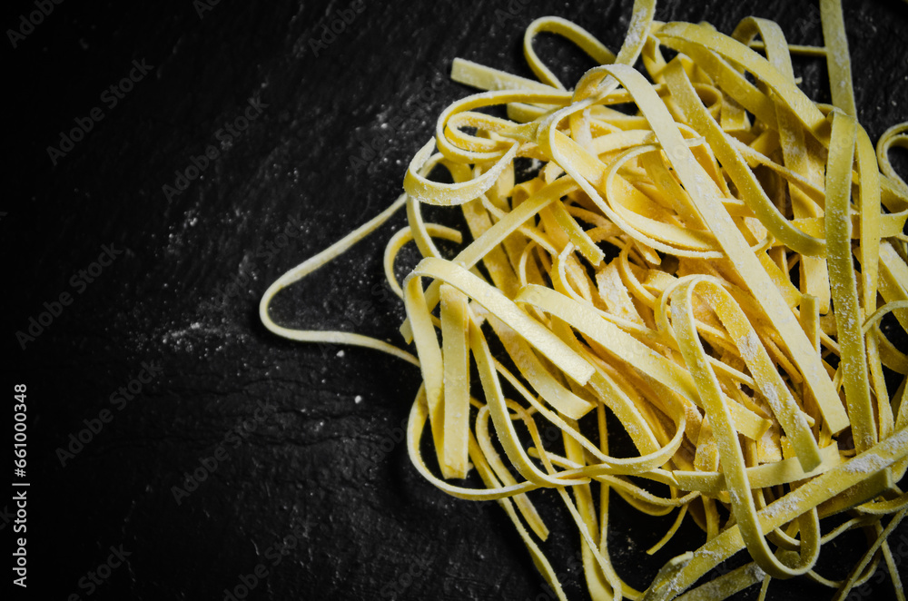 Poster Homemade pasta tagliatelle. On black table.