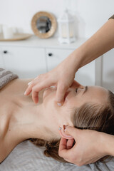 buccal facial massage, close-up, cosmetologist makes woman a procedure on a massage table in a spa salon