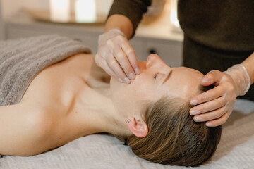 Fototapeta na wymiar buccal facial massage, close-up, cosmetologist makes woman a procedure on a massage table in a spa salon